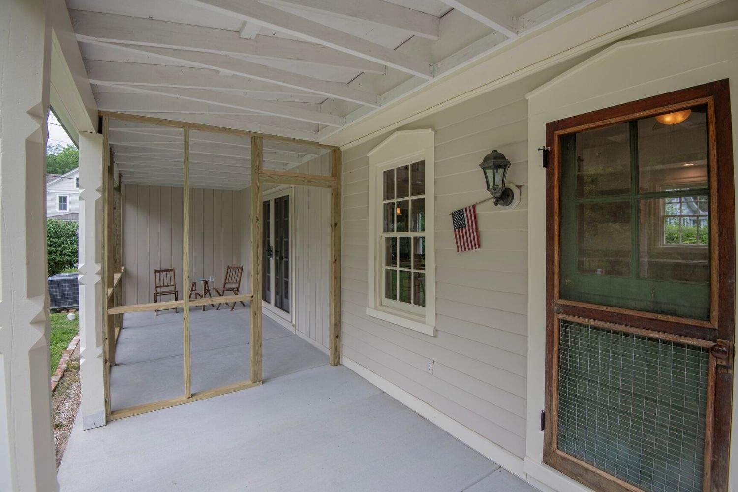 Open rafters and detailed columns enrich the porch, while separate screened and open spaces expand outdoor living opportunities.