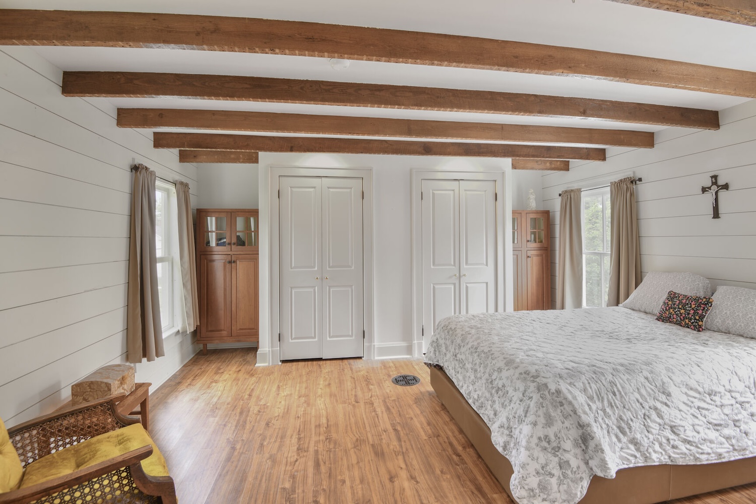 Hand-hewn rafters and clever alcove storage preserve history while enhancing functionality in the primary suite.