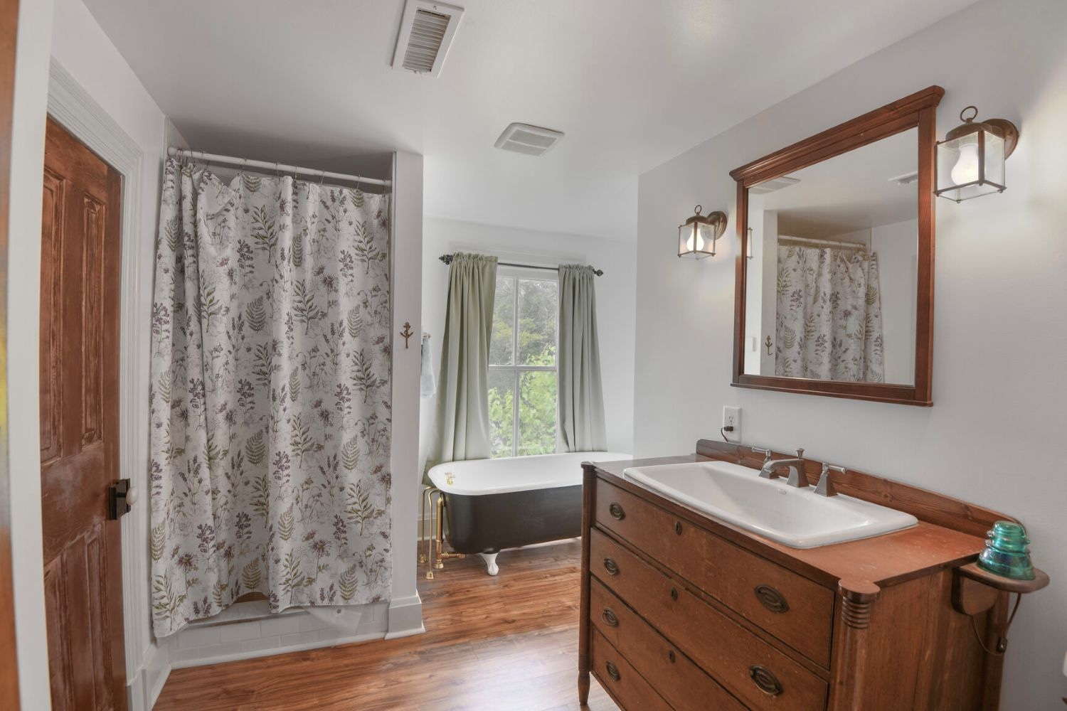 A clawfoot tub and repurposed wood dresser bring distinct charm to the updated hall bathroom.